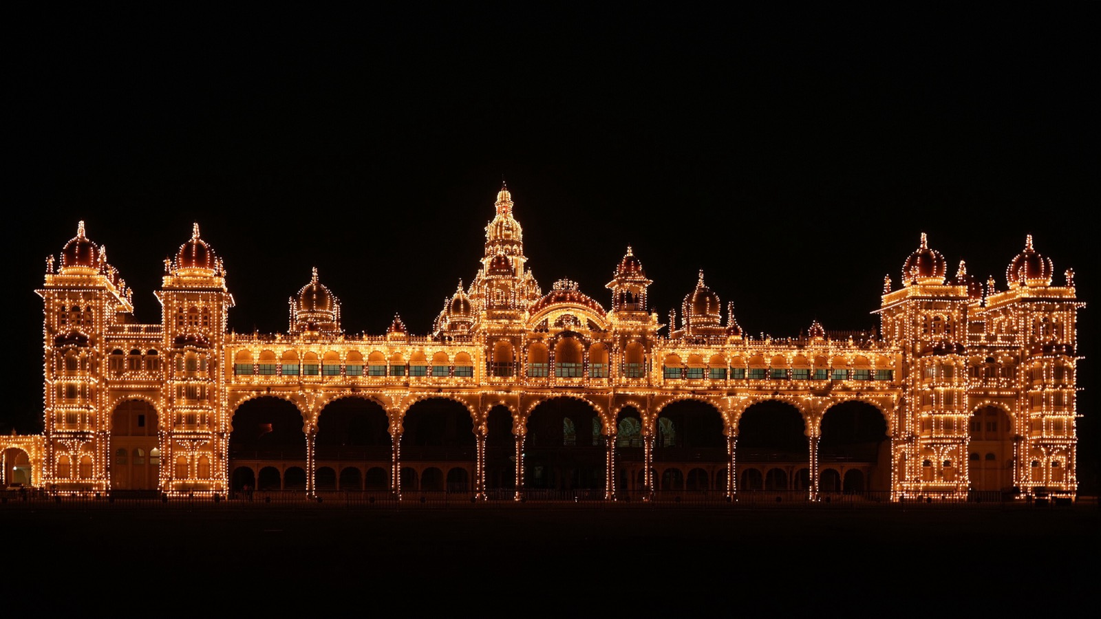 The front of Mysuru Palace outlined in thousands of warm yellow bulbs against a black night sky