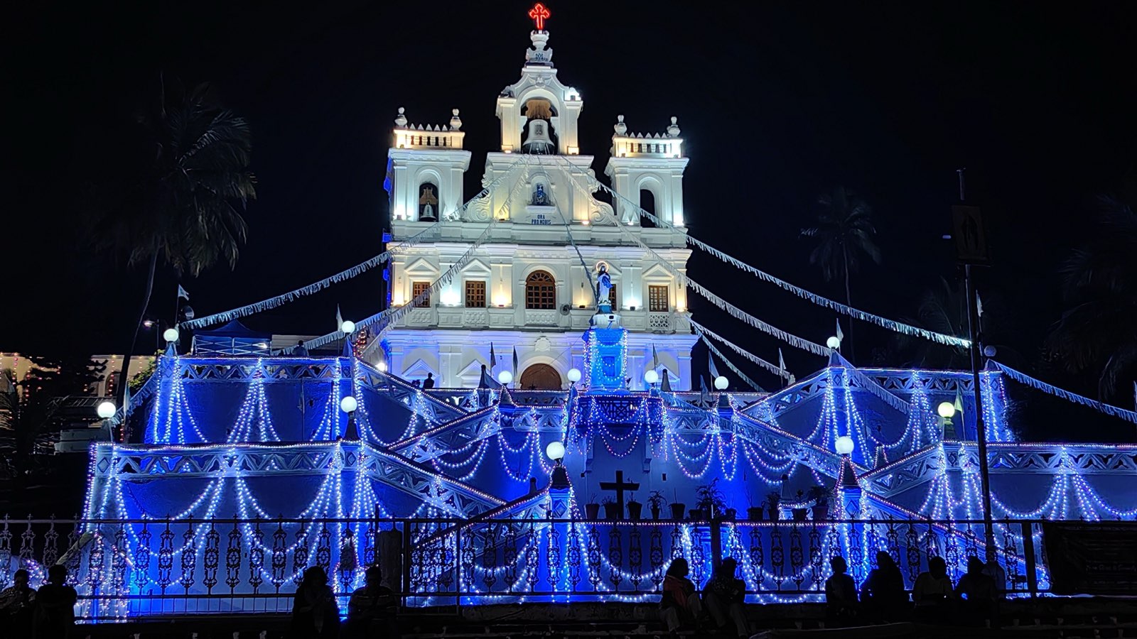 The white church of Our Lady of the Immaculate Conception in Panjim at night, its zigzag stairway strung with blue and white lights