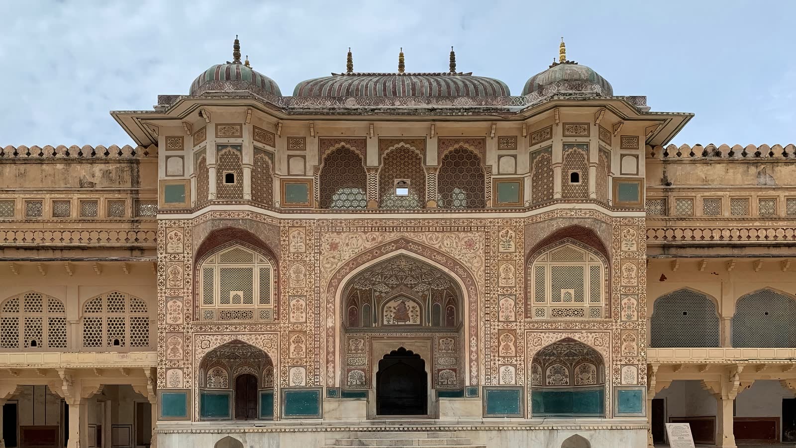 Ganesh Pol at Amer Fort, a tall gateway covered in painted patterns and latticed windows under three small domes