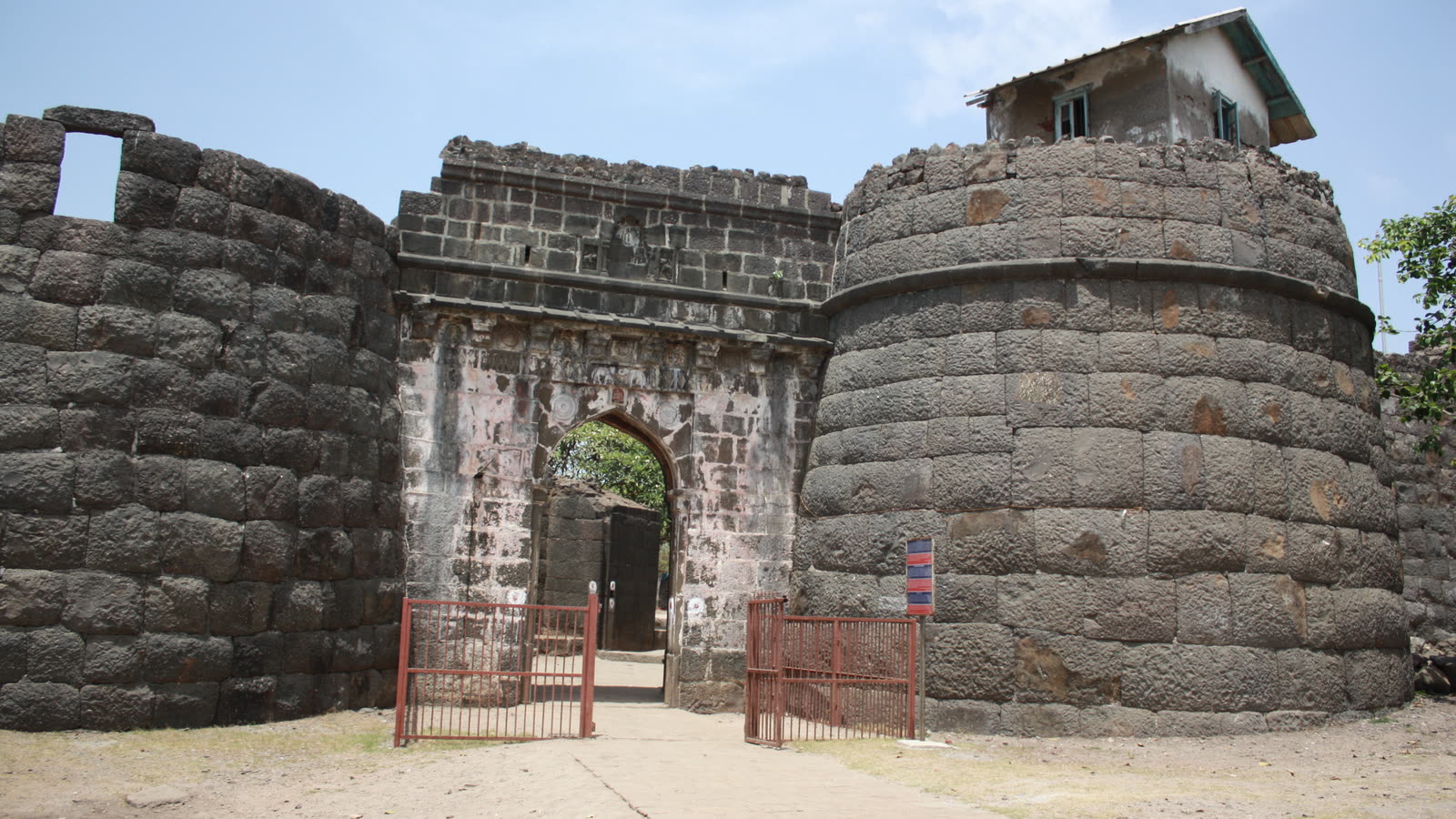 The stone gateway and round bastion of Kolaba Fort in Alibaug, under a blue sky