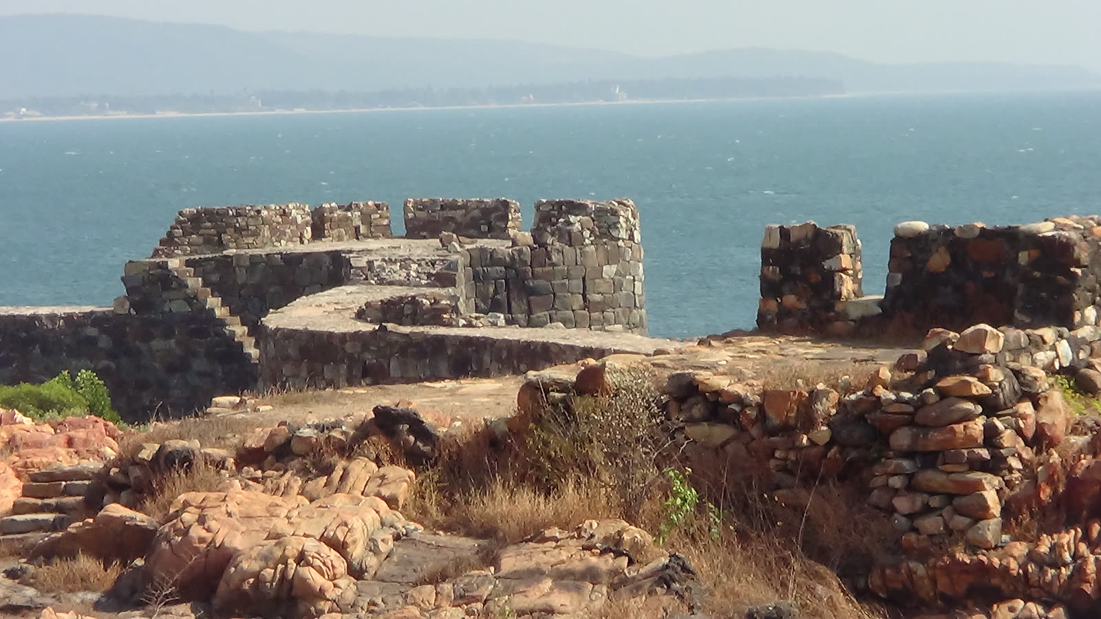 Old stone ramparts of Sindhudurg Fort on the rocks, with the blue sea and the Malvan coast behind