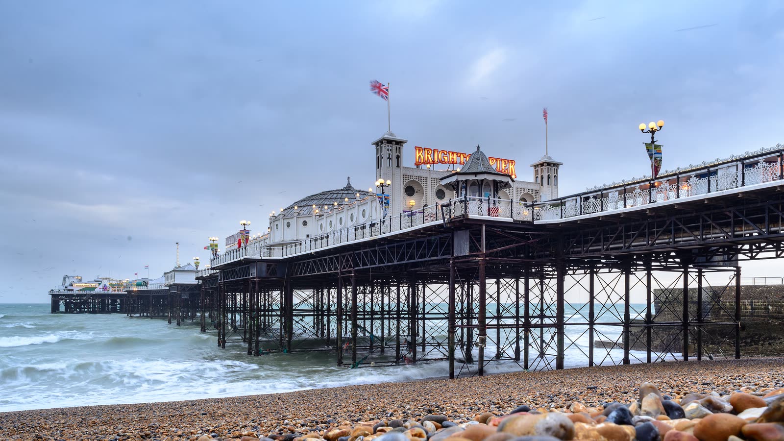 Brighton Palace Pier on iron legs over the waves, seen from the pebble beach