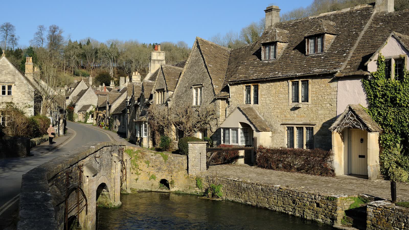 Honey-coloured stone cottages beside a stream and an old bridge in Castle Combe