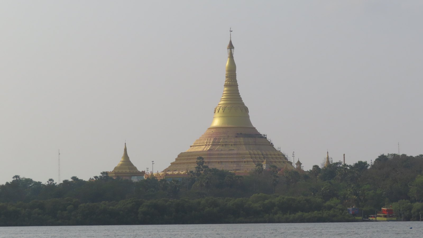 The golden dome and spire of the Global Vipassana Pagoda rising above mangroves across the water at Gorai