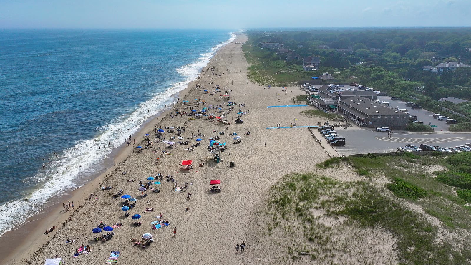 Aerial view of a long sandy beach with umbrellas, dunes and the Atlantic Ocean