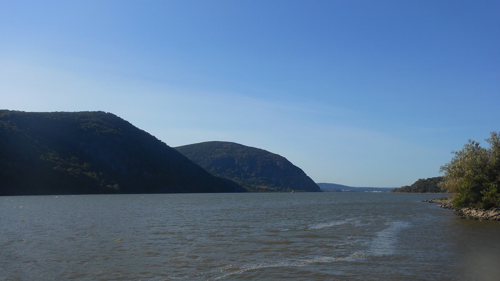 The Hudson River between steep wooded mountains on a clear day