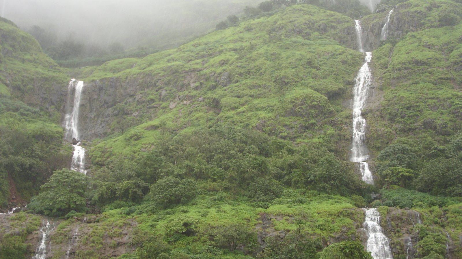 Waterfalls running down green hills at Tamhini Ghat in the monsoon