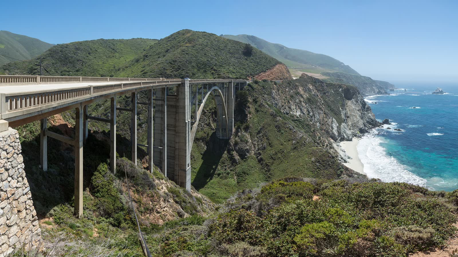 Bixby Creek Bridge on Highway 1 in Big Sur, with green hills and the blue Pacific below