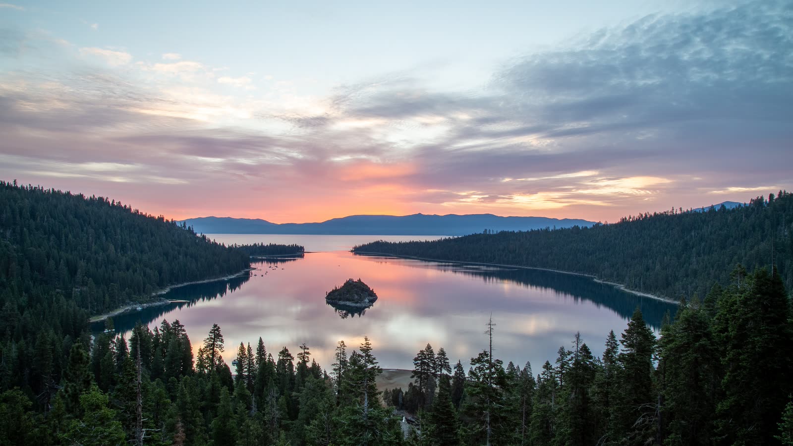 Emerald Bay at sunset, with a small island in the bay and pine forest around it